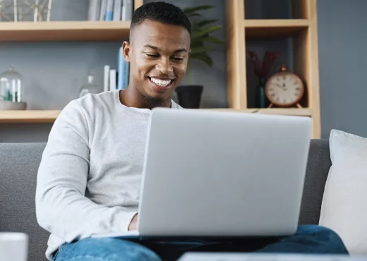 young adult male sitting at home using laptop computer to order checks online