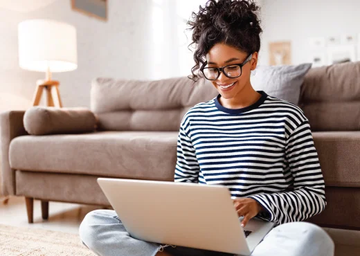 young adult female relaxing against couch with laptop sitting in her lap