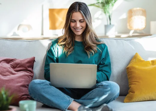young adult female relaxing sitting in couch with laptop sitting in her lap