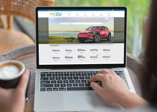 MECU car buying center displayed on laptop computer screen while a young adult female browses for a new car