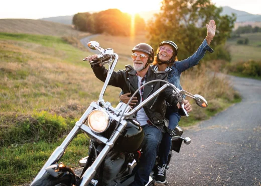 cheery mature couple riding a motorcycle at sunset