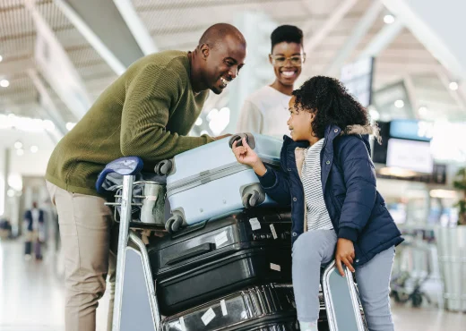 family at airport with stack of luggage excited to travel