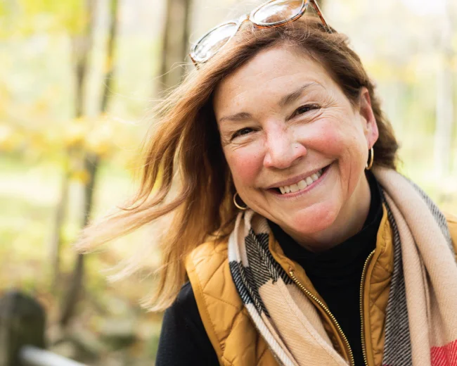 adult female smiling warmly with glasses on top of her head